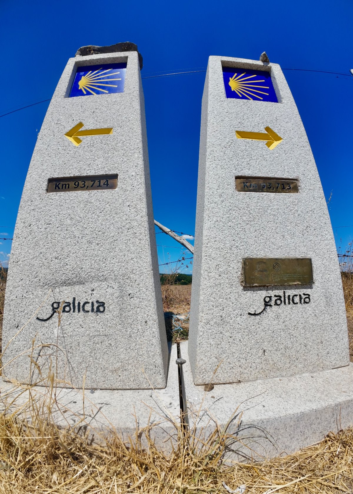 Camino de Santiago waymarkers in Galicia showing the yellow shell and arrows
