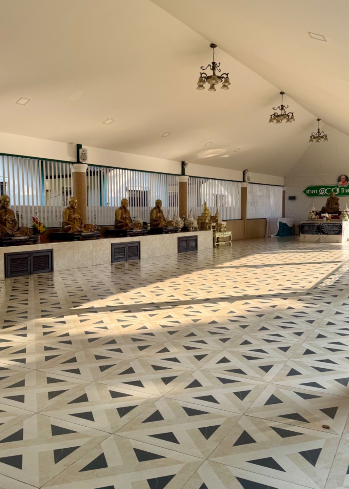 Quiet interior of a Buddhist monastery hall with statues and afternoon light across the floor